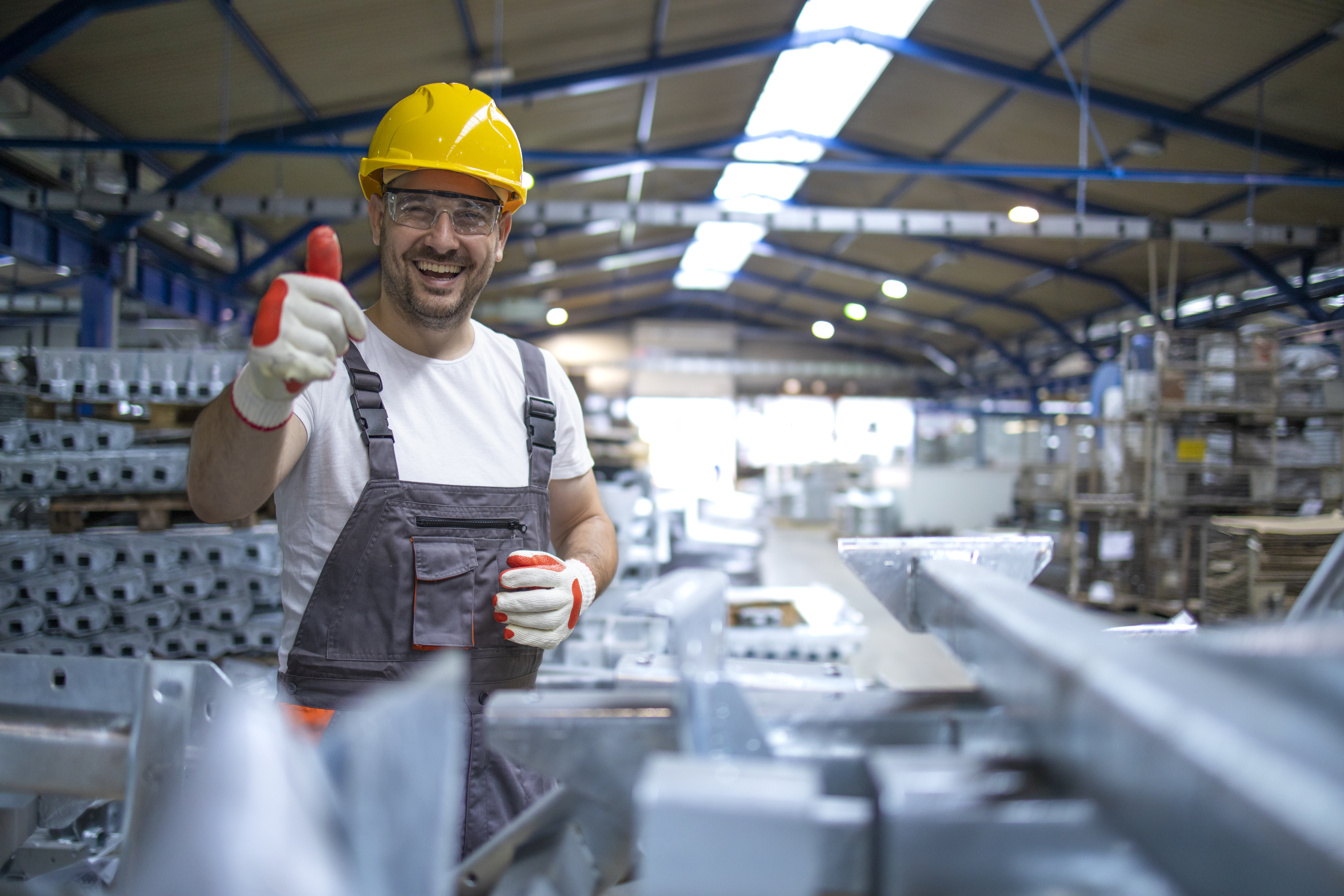 portrait-of-factory-worker-in-protective-equipment-holding-thumbs-up-in-production-hall.jp